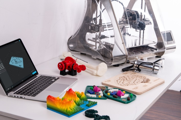 3D printed models next to a 3D printer and laptop